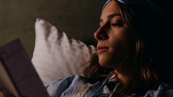 A person reading a book in a calm setting before bed.