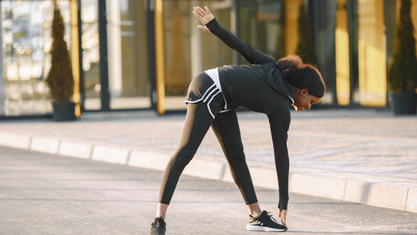 A person stretching outside in morning light, preparing for a run.
