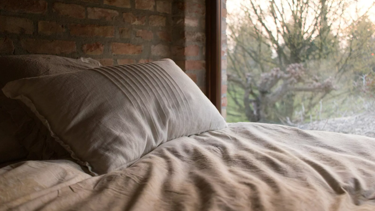 A person stretching their back, suggesting morning discomfort after sleep.