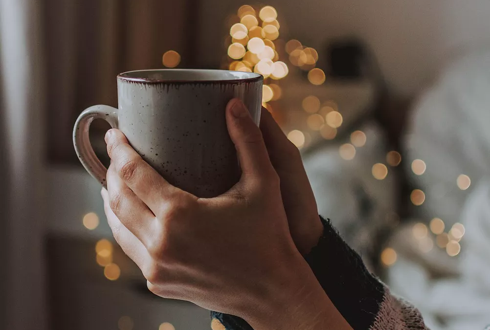 A warm drink being held calmly, suggesting tea or coffee in a daily routine.