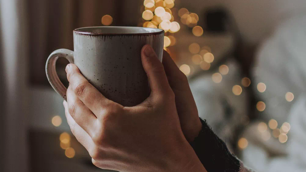 A warm drink being held calmly, suggesting tea or coffee in a daily routine.