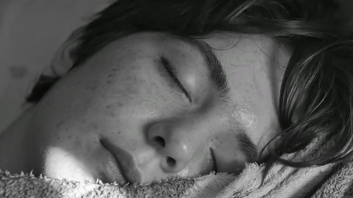 A black and white close-up of a person sleeping with their eyes closed.
