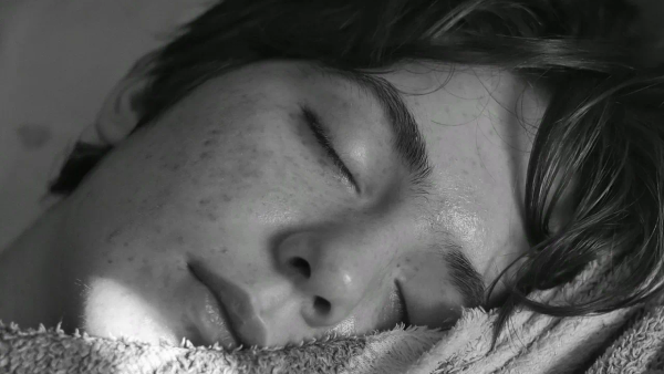 A black and white close-up of a person sleeping with their eyes closed.