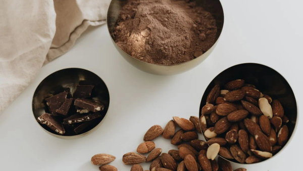 A small bowl of almonds and dark chocolate on a wooden surface, natural sources of magnesium.